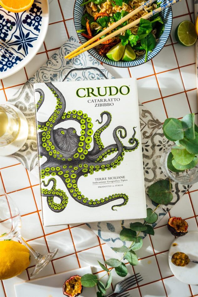 Crudo Catarratto Zibibbo bag-in-box tilted on a checkered tablecloth. Product image.